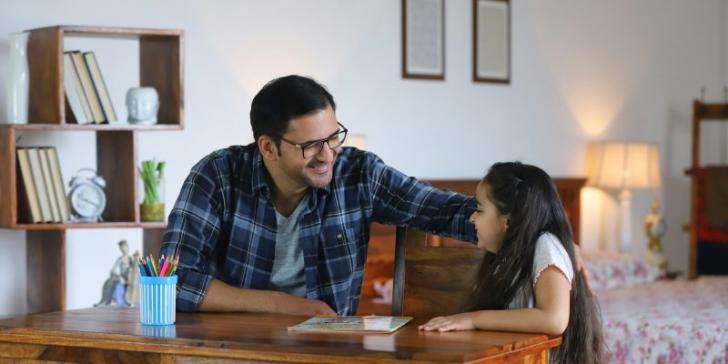 Indian father and her young daughter - studying at home, doing school home work